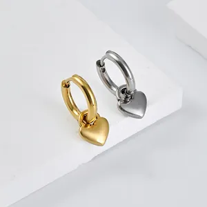 Detail of heart pendant hoop earrings in gold and silver finish on stone base