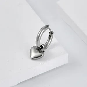 Macro shot of silver heart pendant earring on white stone with polished mirror finish