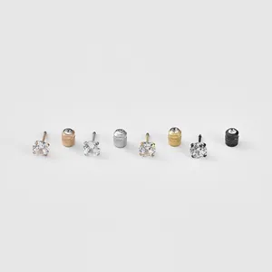 Détails macro de boucles d'oreilles en zircone rose, argent, or et noir avec quatre griffes