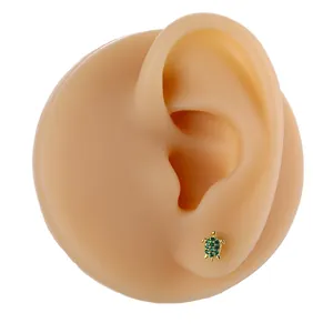 Detailed view of a turtle stud earring in gold with green zircon on a model ear