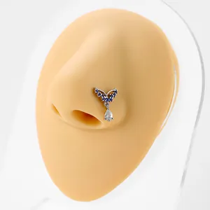 L-shaped silver nose stud with blue wing design and dangling clear teardrop gemstone