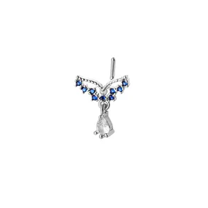 Detail of L-shaped nose stud with blue stones and a teardrop pendant on white background