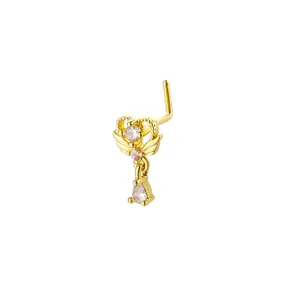Detailed view of L-shaped gold nose stud with heart, wing design and crystal pendant