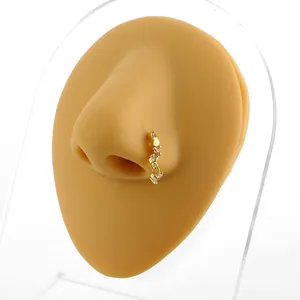 Golden nose ring with triple zircon inlay and fine drop chain on a white background