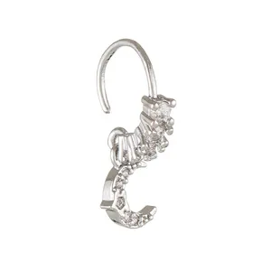Macro shot of silver nose ring with curved hook and sparkling clear zircon stone cross