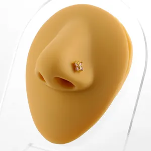 Golden butterfly nose stud with pink zircon stones shown on a professional nose model
