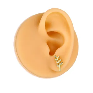Golden branch stud earring with white zircon on silicone ear model for visual display