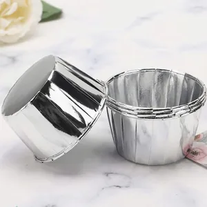 Silver aluminum foil muffin cups on white marble background for professional baking