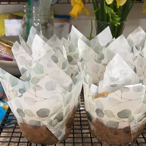 Caissettes tulipes à motif eucalyptus avec muffins fraîchement cuits sur une grille de cuisine