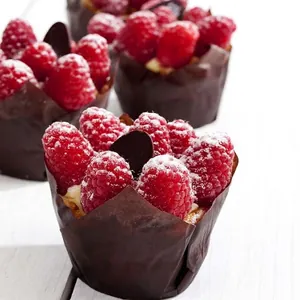 Braune Tulpen-Backförmchen mit frischen Himbeertörtchen auf weißem Hintergrund