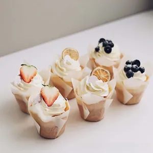 Tulpen-Muffinförmchen mit frisch gebackenen Muffins, garniert mit Erdbeeren und Blaubeeren