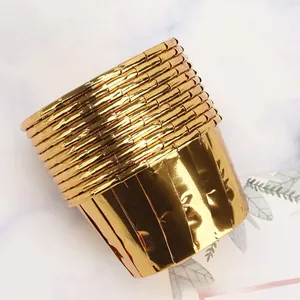 Stack of gold aluminum foil muffin cups on a white marble background for baking decor