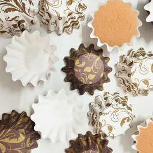 Close-up of patterned greaseproof paper baking cups with elegant gold floral designs