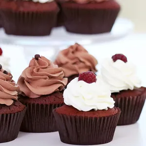Greaseproof paper cupcake liners set with chocolate and red velvet cakes on white base