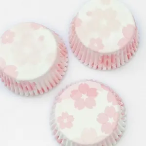 Gros plan de trois caissettes à cupcakes roses à motif sakura sur un tissu blanc