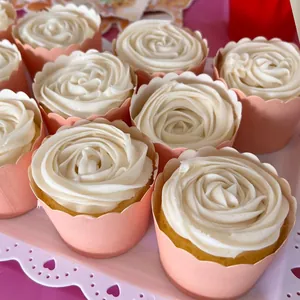 Detalle de moldes de papel rosa para muffins con borde ondulado y crema blanca de rosa