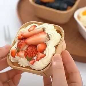 Primer plano de moldes cuadrados de papel kraft con un pastel de fresas frescas