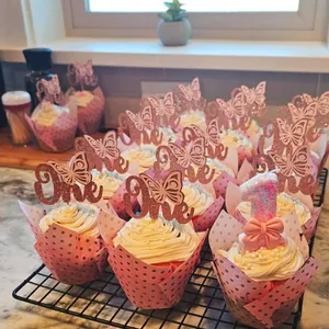 Pink and gold tulip-style cupcake wrappers and butterfly themed cake toppers for birthday party