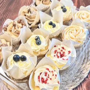 Close-up of assorted cupcakes with cream and berries in tulip paper liners