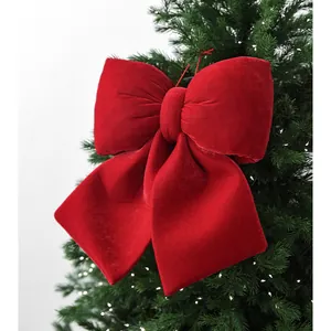Red velvet Christmas bow hanging on a green tree with warm LED lights decoration