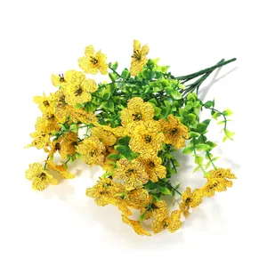 Strauß gelber Kunstblumen mit grünen Eukalyptusblättern auf weißem Hintergrund