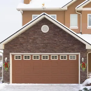 Festoni natalizi a goccia con fiocchi rossi e campane sulla parete di un garage innevato