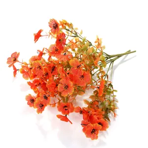 Detail von lebensechten orangefarbenen Kunstblumen mit schwarzen Staubgefäßen und Blättern