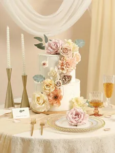 Primer plano de rosas y peonías artificiales de seda decorando un pastel de bodas blanco