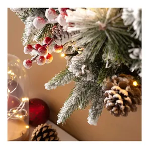Close-up of frosted pine needles with red berries and warm LED lights on a Christmas wreath