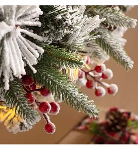 Detail of flocked Christmas wreath with red berries and warm LED lights on pine needles