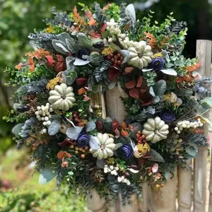Herfstkrans met eucalyptusbladeren, witte pompoenen en paarse bloemen aan een bamboe hek