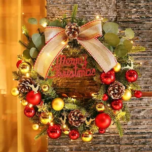 Detail of Christmas wreath with pine cones, red gold ornaments, and warm LED lights