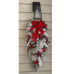 Close-up of flocked Christmas teardrop swag with pine cones and red velvet bow