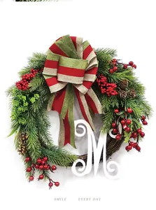 Detailed view of Christmas wreath featuring red berries, pine cones, and a wooden letter M