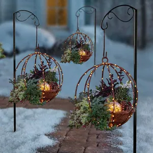 Cesto appeso da esterno con luci LED calde e pigne in un giardino innevato