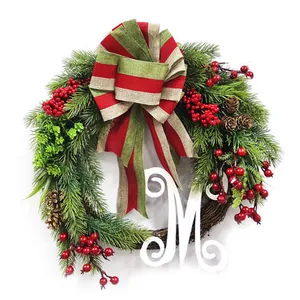 Christmas wreath with green needles, red berries, pinecones, and a white letter M