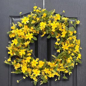 Vibrant yellow faux cosmos flower wreath with eucalyptus leaves on a dark wooden door
