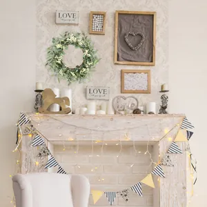 Detail of faux eucalyptus wreath with white berries hanging on a cozy indoor fireplace mantel