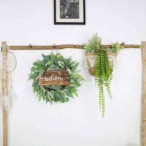 Detail of faux eucalyptus wreath with welcome sign and woven hanging basket decor
