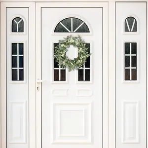 Close-up of artificial eucalyptus wreath with small white flowers on a white front door