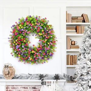 Corona de Pascua con flores rosas y moradas y eucalipto verde en una pared blanca