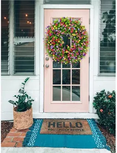 Corona de flores de Pascua en tonos pastel y eucalipto colgada en una puerta rosa