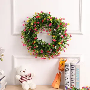 Corona de Pascua con hojas verdes y flores coloridas en una decoración de pared blanca