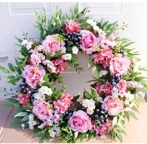 Close-up of artificial flower wreath with pink roses, white blooms and green leaves