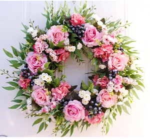 Detail of pink faux roses and lush green leaves on a spring wedding floral wreath