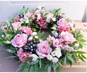 Close-up of decorative wreath with pink roses, hydrangeas, and berries on a white door