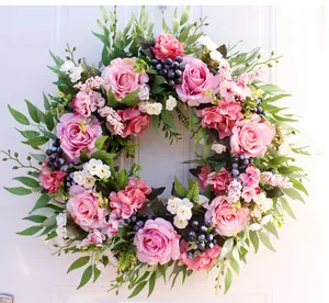 Close-up of artificial floral wreath with pink roses, white daisies, and green foliage