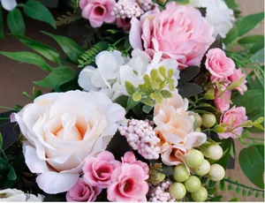 Close-up of pink roses and white flower clusters in a handmade floral wreath decoration