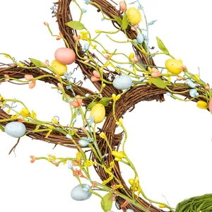Osterhasen-Kranz aus Rattan mit bunten Eiern und grünen Blättern für die Türdekoration