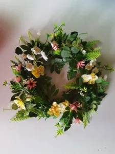 Close-up of Easter wreath with yellow orchids, pink flowers and green leaves on vine ring